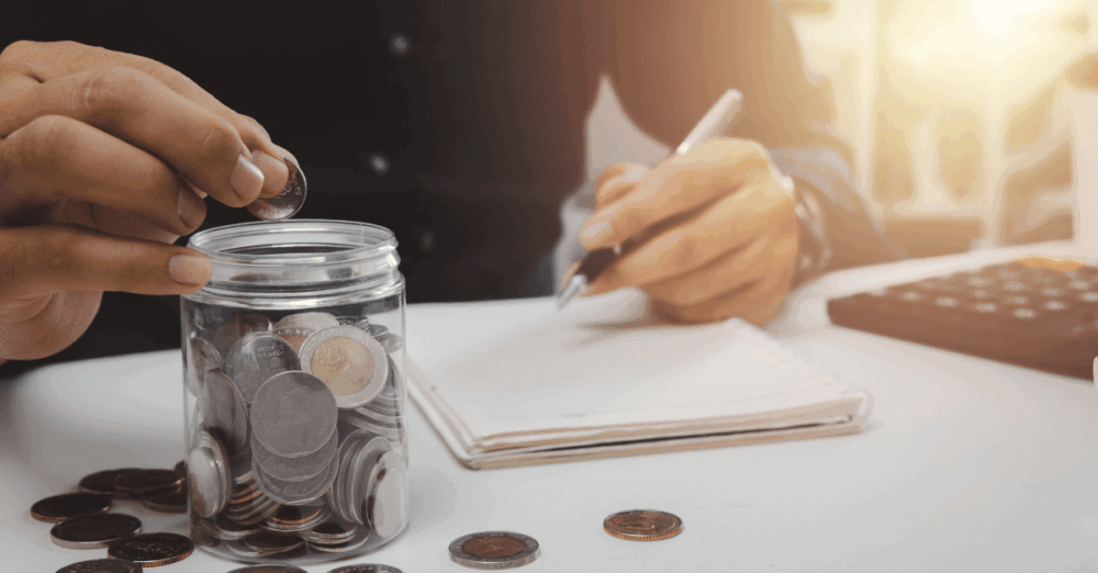 Mann am Tisch mit Blog, Stift und Geld, zählt die ersten 10.000 Euro